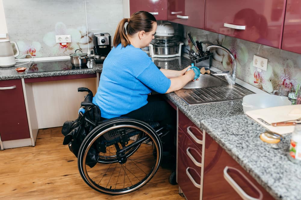 A disabled woman sitting in a wheelchair, washing the dishes