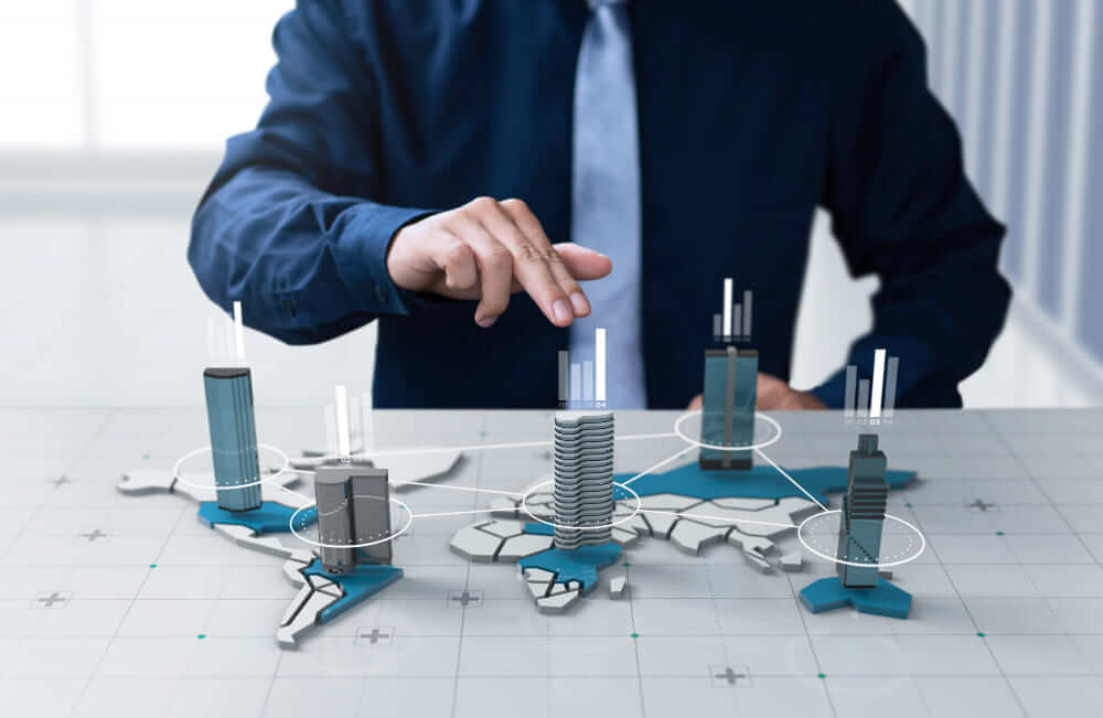 A man pointing at a model of miniature skyscrapers on world map.